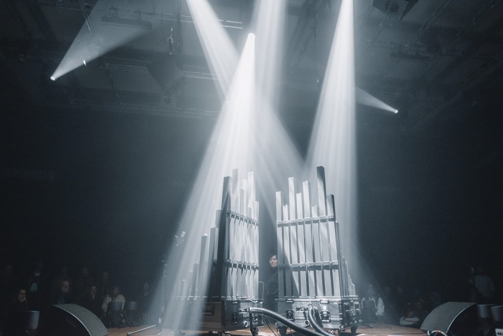 BLACK SQUARE wind-dynamic pipe organ by gamut inc on stage at Radialsystem Berlin, twin pipe modules lit by crossing beams