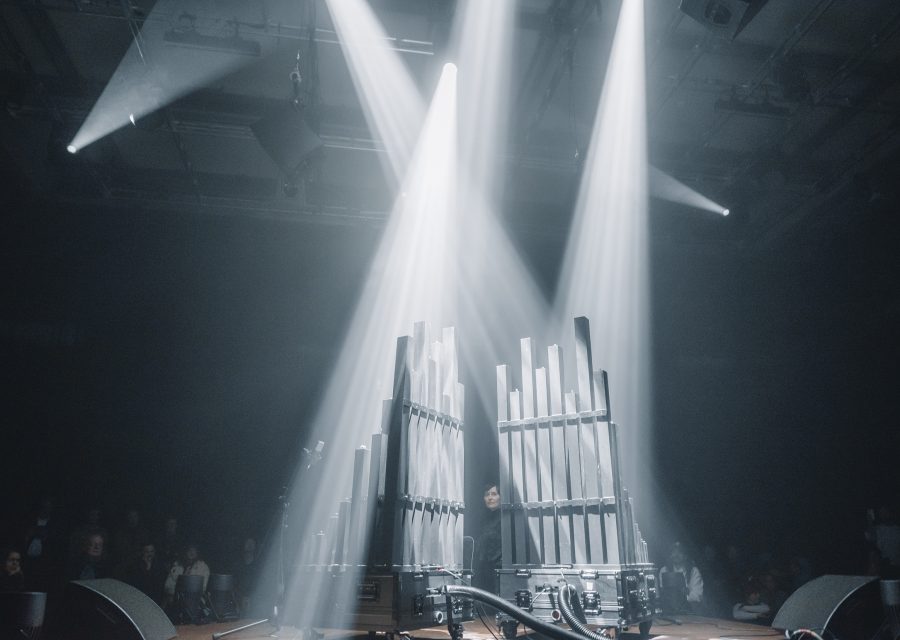 BLACK SQUARE wind-dynamic pipe organ by gamut inc on stage at Radialsystem Berlin, twin pipe modules lit by crossing beams
